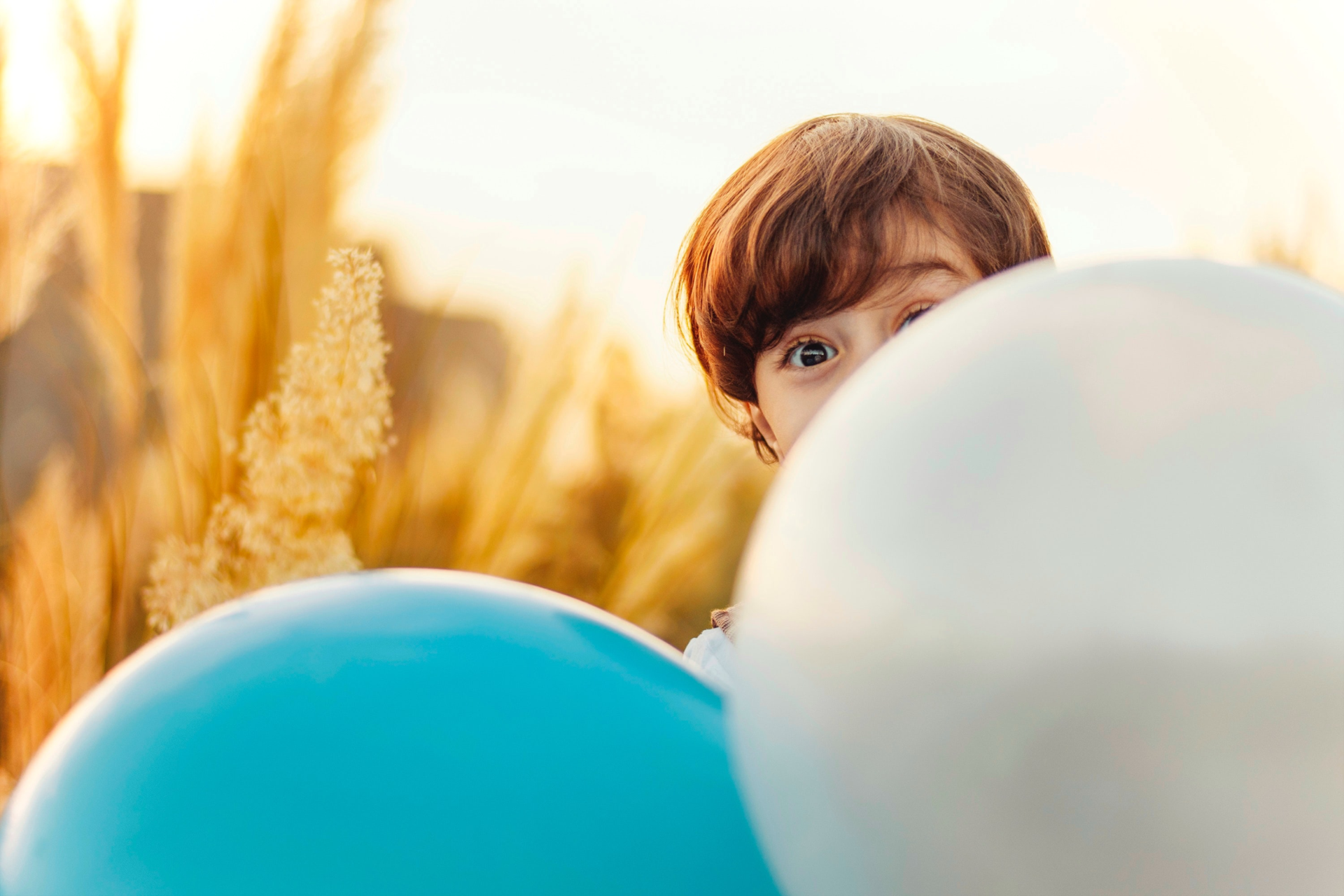 Kind schaut hinter Luftballons hervor