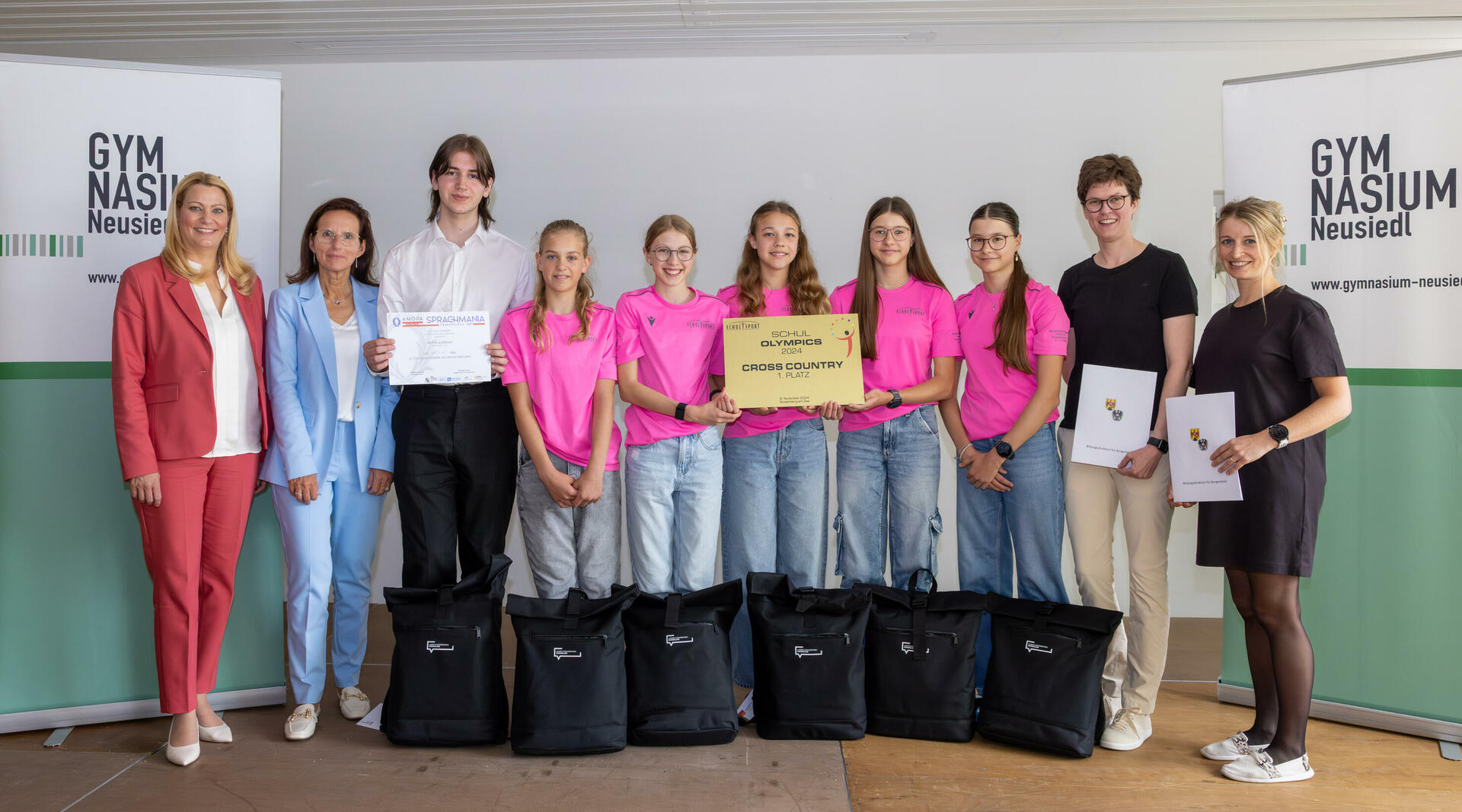  LRin Mag.a (FH) Daniela Winkler mit der Direktorin des BG/BRG Neusiedl, OStRin Mag.a Tanja Bayer-Felzmann,  Viktor Aubrecht, dem Bundesmeister der AMOPA Sprachmania 2025, den Bundesmeisterinnen im Schul Olympics Cross Country 2024 Anna Haubenwallner, Lieselotte Gettinger, Greta Bohrer, Stella Bohrer und Lisa Zechner mit ihren Lehrerinnen Mag.a Lisa Mauersics und Mag.a Theresa Wagner.
