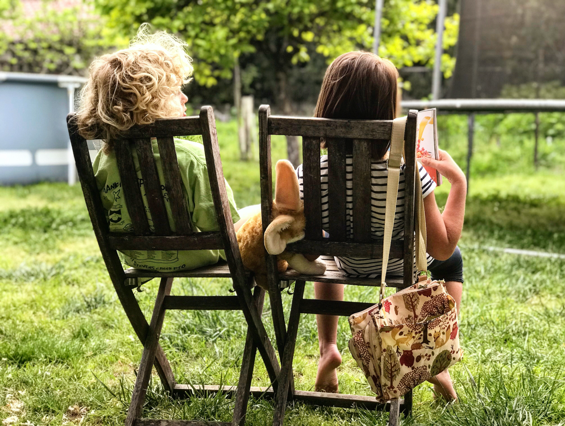 Kinder sitzen im Garten auf Gartenstühlen