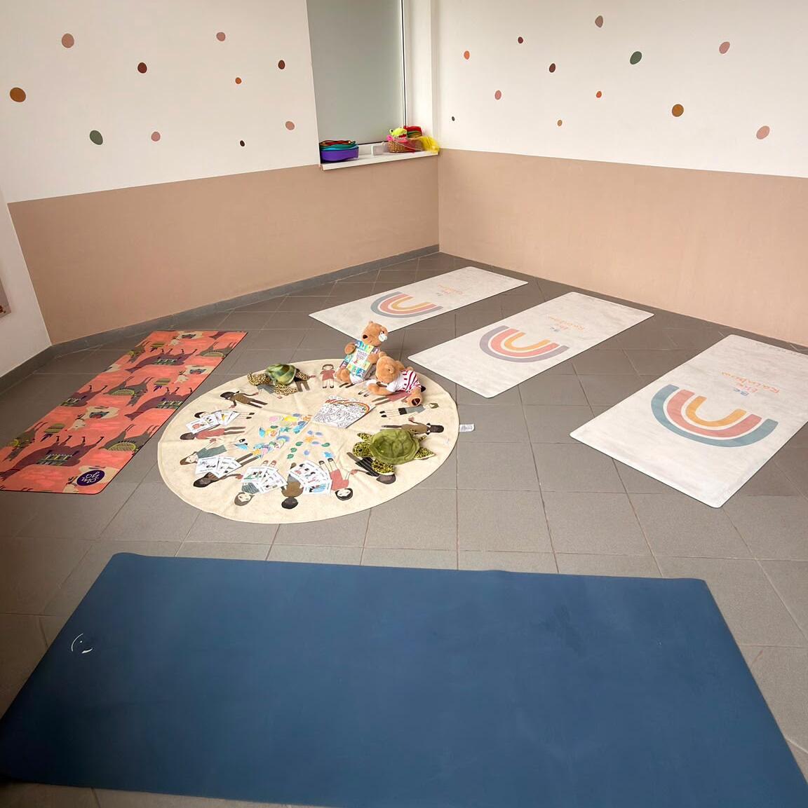 Ruheecke mit gepolsterter Bank, gefalteter Decke und blauer Matte im Kinderzimmer